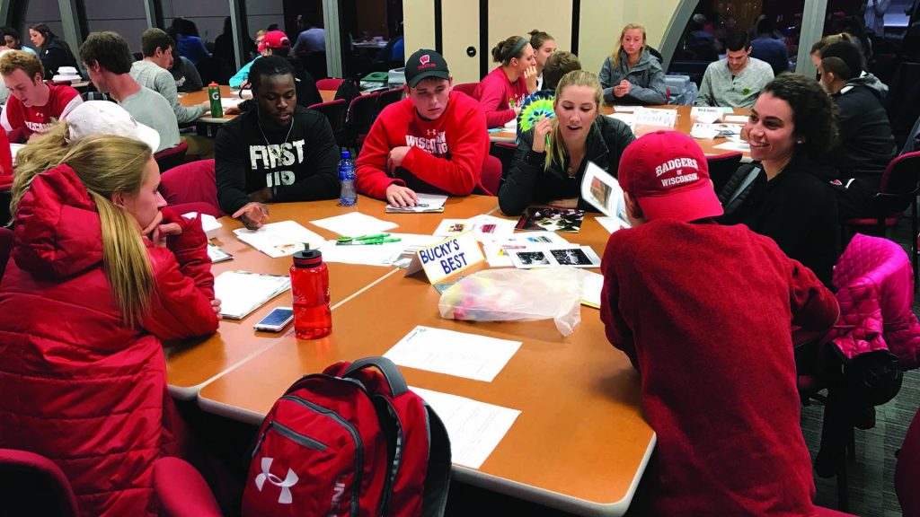 Student athletes gathered around a table in discussion.